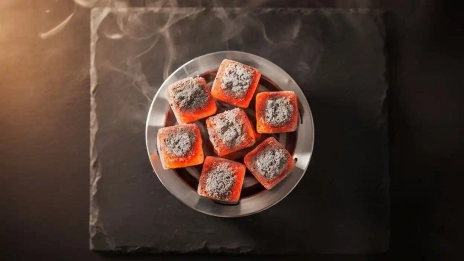 Glowing coconut shell hookah charcoal cubes on a heat management device showing steady heat performance for a smooth hookah session.